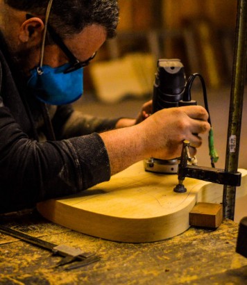 Luthier moldando o corpo de um instrumento com uma tupia